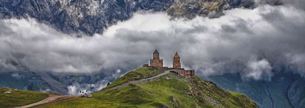 Kazbegi Kirche vor Bergpanorama mit Wolken in Georgien