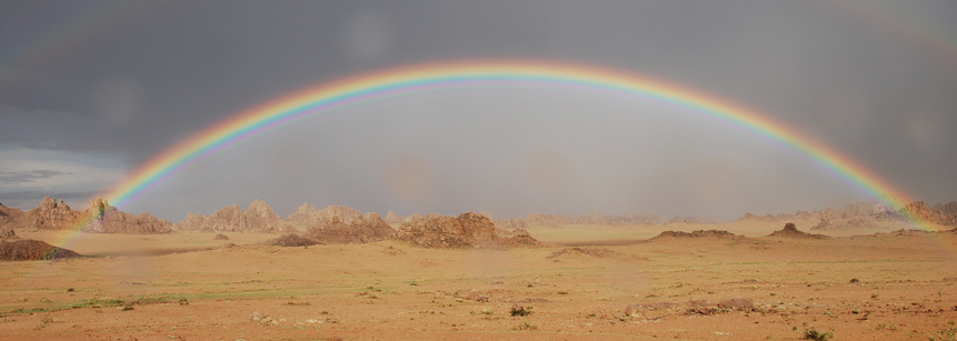Vor der noch grau verhangenen Kulisse kommt der bunte Regenbogen auf unserer Mongolei Rundreise besonders schön zur Geltung