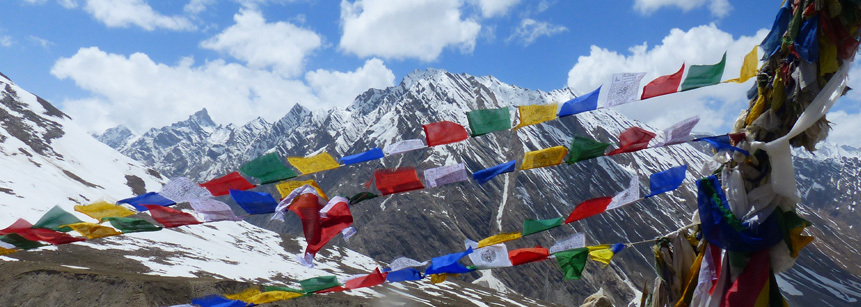 Bunte Gebetsfahnen im  Wind vor schneebedeckten Bergen des Himalayas in Nordindien