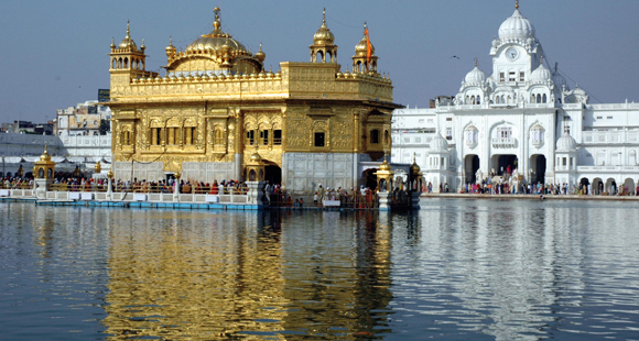 Blick auf den Goldenen Tempel in Amritsar mit Pilgern und einer Spiegelung im See