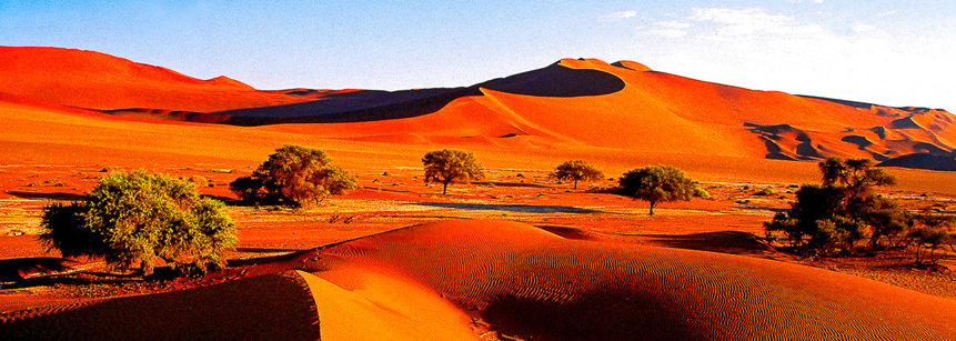Im Sonnenlicht rot leuchtende Sanddünen von Sossusvlei in Namibia