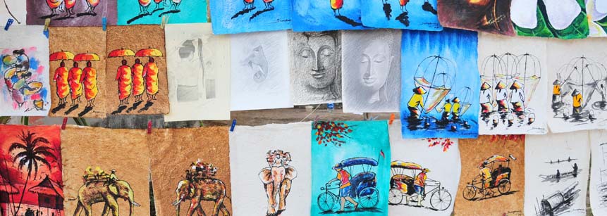 Verschiedene Gemälde mit laotischen Motiven wie Mönchen, Buddhas, Elefanten, die an einer Leine zum Verkauf hängen an einem Stand in Vientiane in Laos