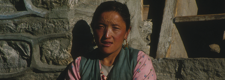 Lachende nepalesische Frau vor einer Mauer auf einer Nepal Reise nach Helambu und Langtang.