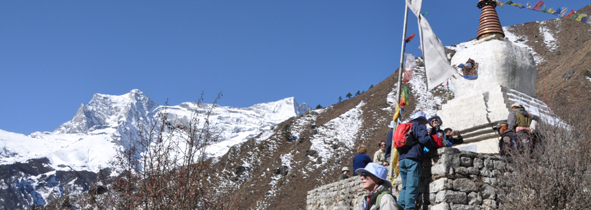 Stupa mit Wanderern und schneebedeckten Bergen oberhalb der Ortschaft Khunde im Mount Everest Gebiet auf einer Nepal Reise