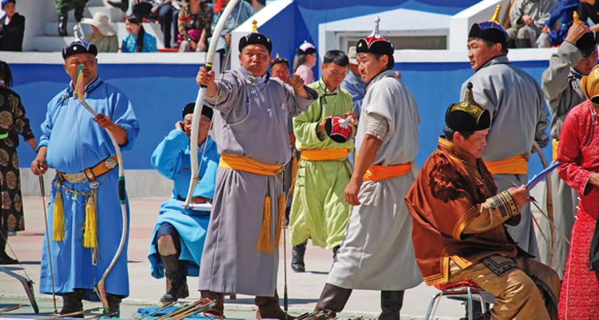 Nomaden beim Bogenschiessen in Ulan Bator auf dem Naadam Fest während einer Mongolei Reise.