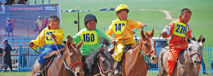 Kinderjockeys bei einem Pferderennen zum Naadam Fest auf einer Mongolei Reise