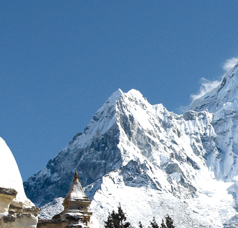 Aussicht auf den schneebedeckten Berg Amadablam mit einer Stupa im Vordergrund auf einer Trekking Reise in Nepal