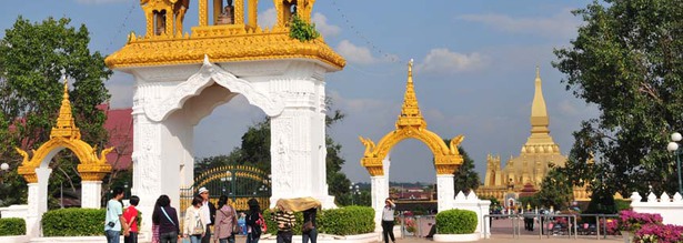 Blick auf den Pha That Luang Tempel in der laotischen Hauptstadt Vientiane mit den Eingangsportalen und Besuchern im Vordergrund