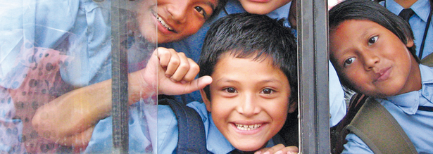 Lachende Kinder, die aus einem Busfenster winken in Nepal