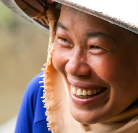 Lachende Vietnamesin mit traditionellem Hut