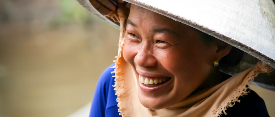 Lachende Vietnamesin mit traditionellem Hut